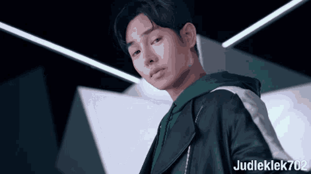 a young man wearing a green hoodie and a black jacket with judleklek702 on the bottom right