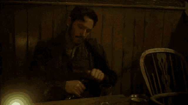 a man sitting at a table pouring a bottle of alcohol with a label that says ' sd ' on it