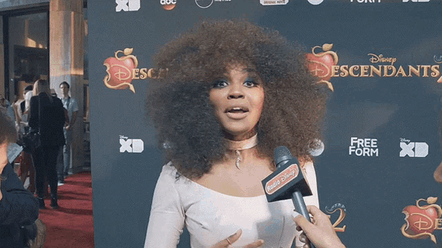 a woman on a red carpet with a microphone that says hello disney