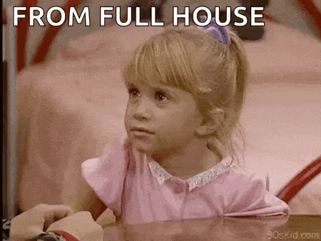 a little girl in a pink shirt is sitting at a table with a person .
