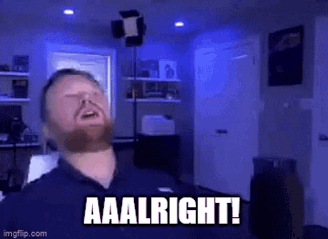 a man with a beard is standing in a dark room with the words aaalright written on his face