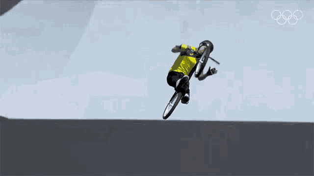 a person is doing a trick on a bike in front of a sign that says olympics