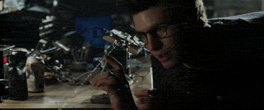 a man wearing glasses is looking at a piece of equipment