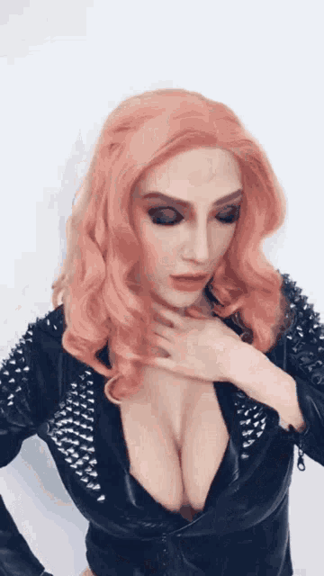 a woman with pink hair is wearing a black leather jacket with studs