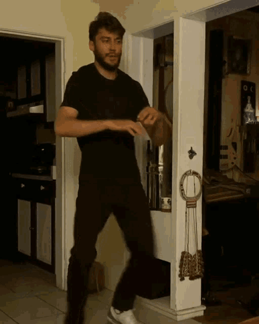 a man in a black shirt is standing in front of a door