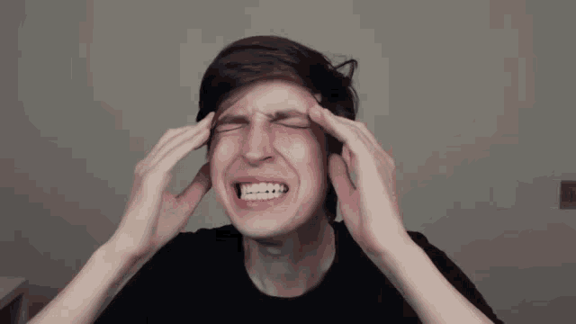 a man is making a funny face while holding his head with his hands .