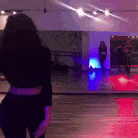 a woman in a black top is standing in front of a mirror in a dance studio