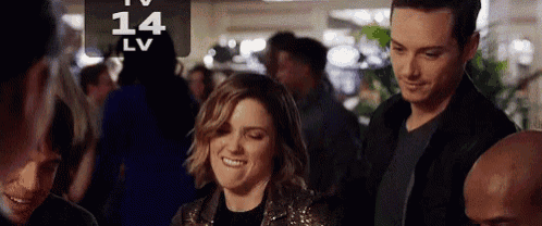 a man and a woman are standing next to each other in a crowd and smiling .