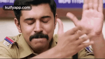 a police officer with a mustache is covering his ears with his hands .