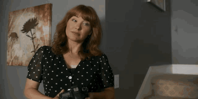 a woman in a polka dot dress holds a camera