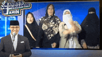 a man in a suit stands in front of a microphone in front of a sign that says " amin "