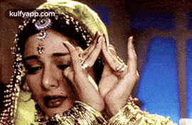 a woman is holding her head with her hands while wearing a veil and jewelry .