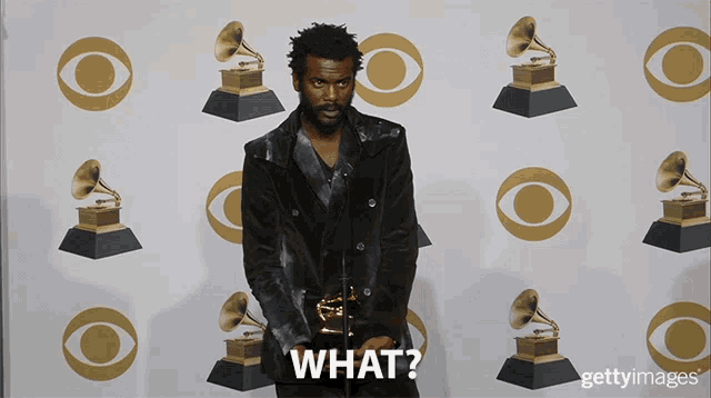 a man standing in front of a wall of grammy awards says what