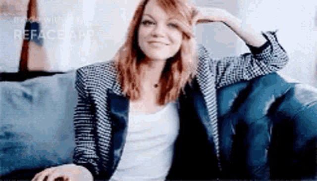 a woman is sitting on a couch with her hand on her head and smiling .