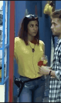 a woman in a yellow shirt stands next to a man in a plaid shirt holding a glass of wine
