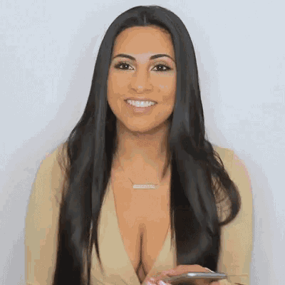 a woman with long black hair is smiling and holding a phone