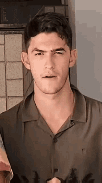 a young man wearing a polo shirt is looking at the camera with a serious look on his face