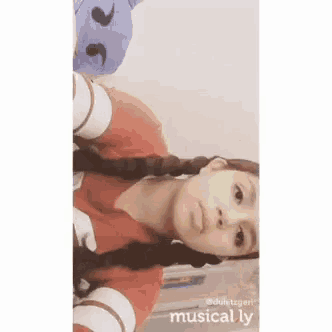 a girl with braids is taking a selfie with a stuffed animal .