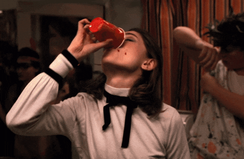 a woman drinking from a red cup with a stain on her face