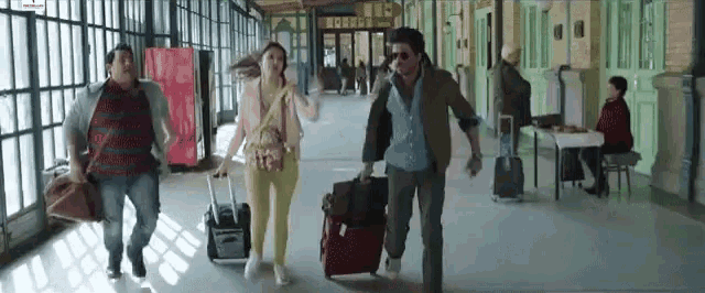 a group of people are walking down a hallway with suitcases .