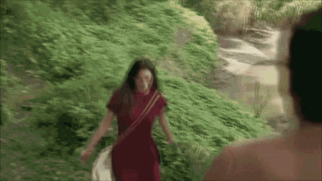 a woman in a red dress is walking through a grassy field