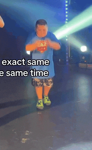 a boy in a blue shirt is dancing on a stage with the words exact same same time above him