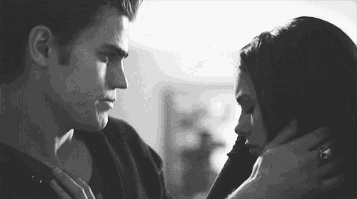 a black and white photo of a man and a woman looking into each other 's eyes .