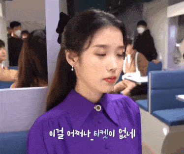 a woman wearing a purple shirt and red lipstick is sitting in a diner