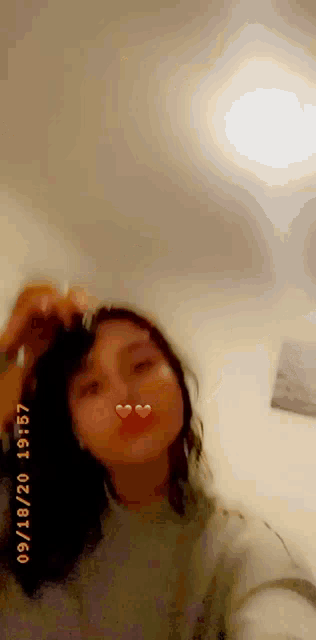 a woman is taking a selfie with two hearts on her lips .