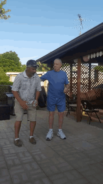 two men are standing on a patio under a covered area