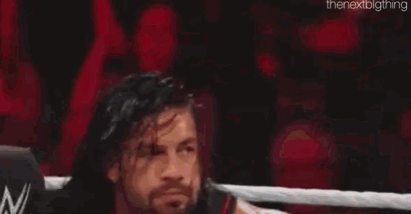 a wrestler is standing in a ring with a pink rope .