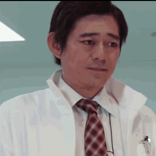 a man wearing a white coat and a plaid tie has a pen in his pocket