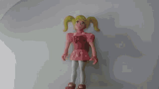 a doll with blonde pigtails and a pink dress is standing on a white surface