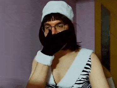 a woman wearing a santa hat and gloves covering her mouth