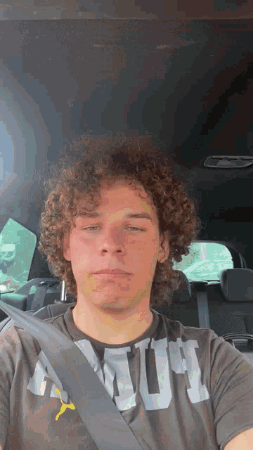 a young man with curly hair is wearing a shirt that says armour