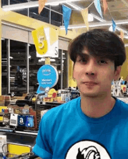 a man in a blue shirt is standing in a grocery store and looking at the camera .