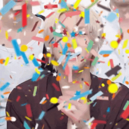 a man is standing in front of a bunch of confetti flying around him .