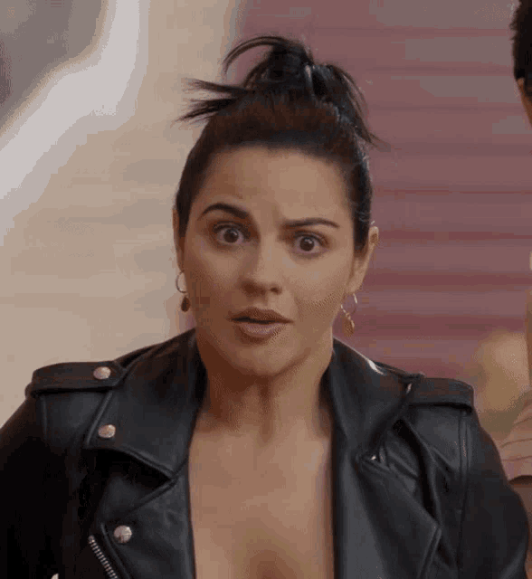 a woman wearing a black leather jacket looks surprised