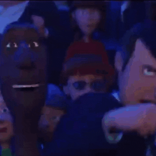 a man in a suit and bow tie is making a funny face in front of a crowd of people .