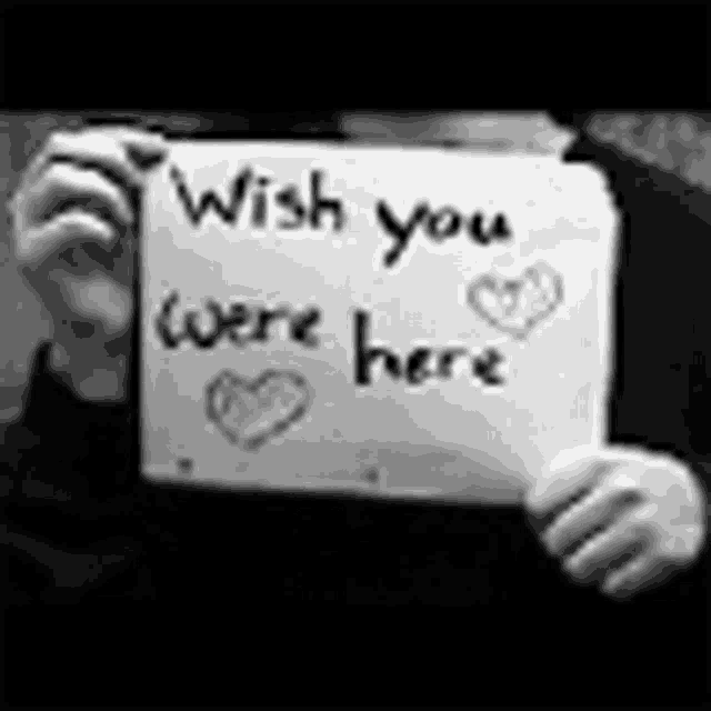 a person is holding a paper that says `` wish you were here '' .
