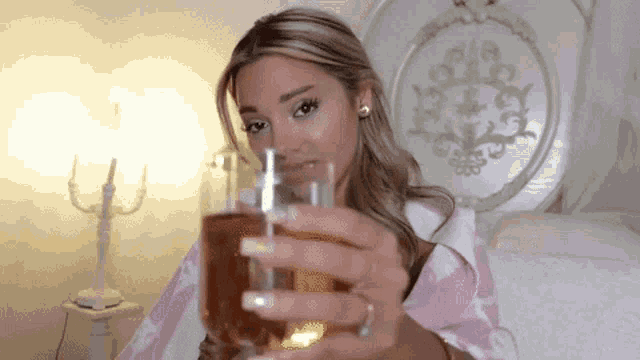 a woman in a pink robe is holding a glass of wine in her hand .