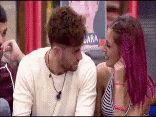 a man and a woman are looking at each other . the woman has purple hair .