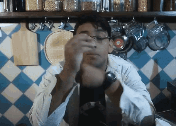 a man wearing glasses is standing in front of a kitchen counter