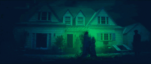 a group of people standing in front of a house that is lit up with green lights