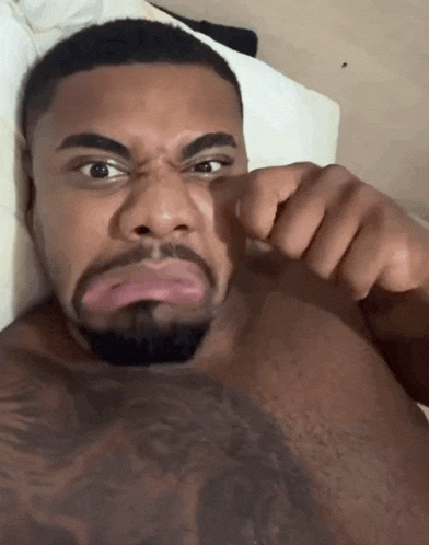 a shirtless man with a tattoo on his chest making a funny face