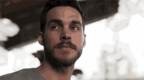 a close up of a man with a beard and mustache looking up .