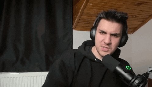 a man wearing headphones and a microphone is making a face .