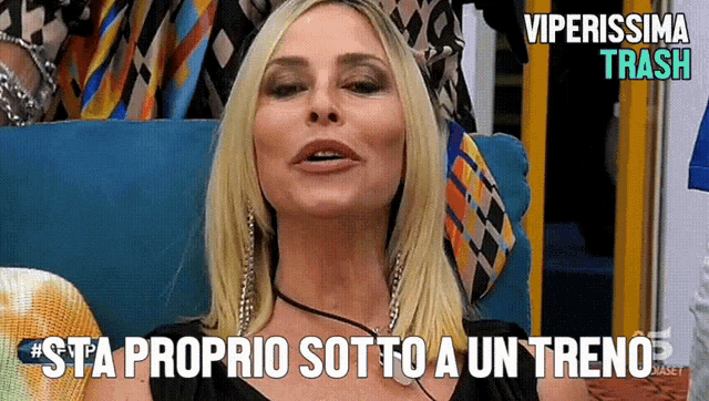 a woman sitting on a couch with the words sta proprio sotto a un treno on the bottom