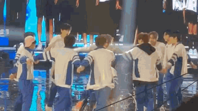 a group of people are standing in a circle on a stage holding hands .