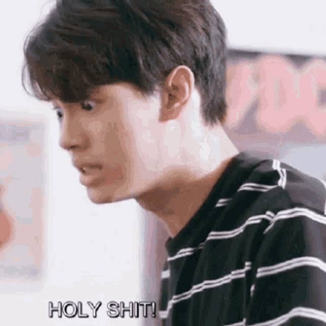 a young man in a black and white striped shirt is making a funny face .